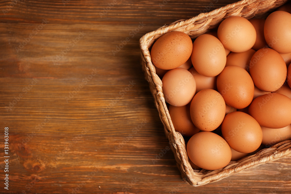 Raw eggs in basket on wooden background Raw eggs in basket on wooden background