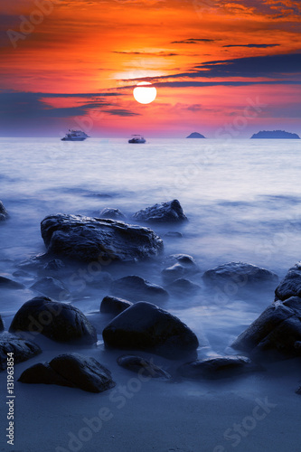 Sunset Ocean Long time Exposure  Blurred Ocean Waves with Stones  Sun and Boats.