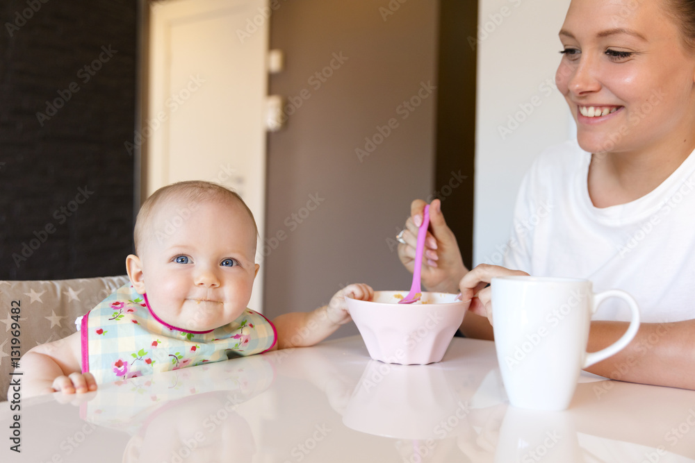 Caring young mother feeds her smiling baby girl Caring young mother feeds her smiling baby girl