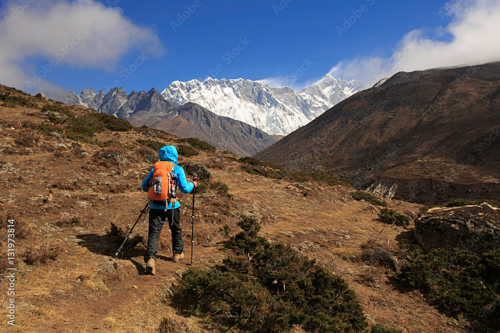 young woman backpacker trekking on himalaya mountains,drying socks with sunshine on the backpack