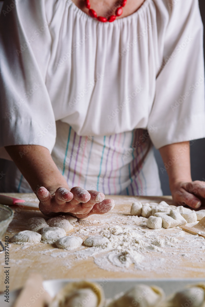 Front view of woman's hands making dough for meat dumplings.