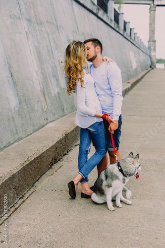 Beautiful young couple playing with a dog husky in a park. Summer outdoors.