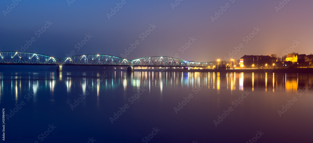 Panoramic view of road bridge over Vistula river in the night. Torun, Poland.
