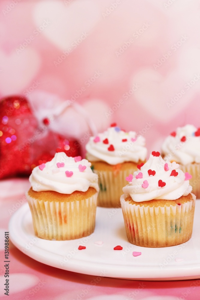 Homemade Valentine cupcakes topped with heart shaped sprinkles on Pink background,selective focus