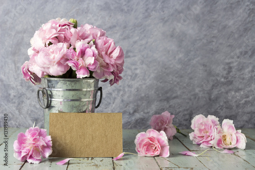 Pink carnation flowers in zinc bucket and blank brown card