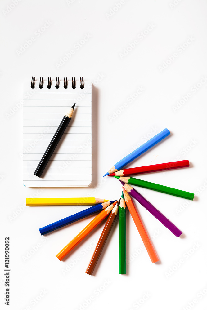 Note book with color pencils on white background