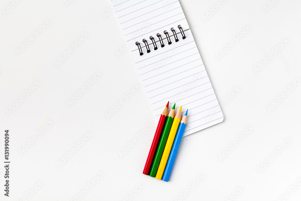 Note book with color pencils on white background Note book with color pencils on white background