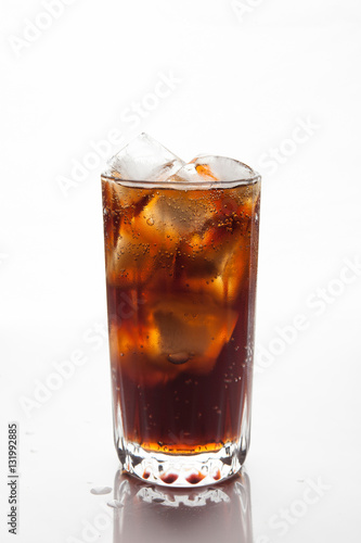 Cola with ice in a glass on white background