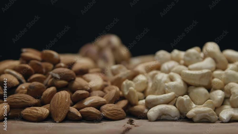 Piles of mixed nuts on a wooden table isolated on black, rotating Piles of mixed nuts on a wooden table isolated on black, rotating