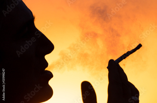 Silhouette of male smokers in the sunset photo