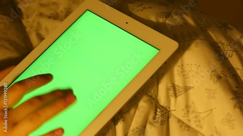 A man uses a green screen tablet pc on bed