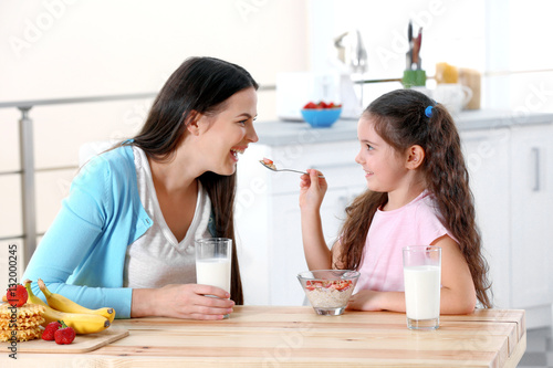 фотографія Mother and daughter having healthy breakfast in kitchen