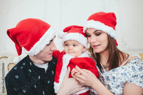 young couple with a baby in a red cap celebrate new year
