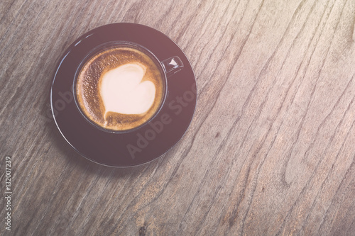 Hot latte coffee in black cup on grey wooden table background. V