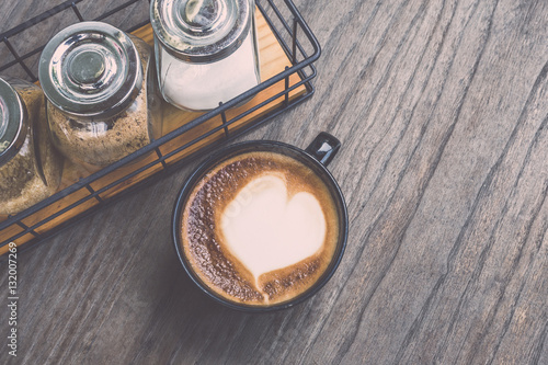 Hot latte coffee in black cup on grey wooden table background. V