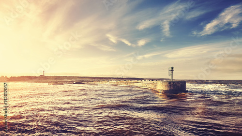 Sunset over port entrance in a storm, color toned picture, Ustka, Poland. photo