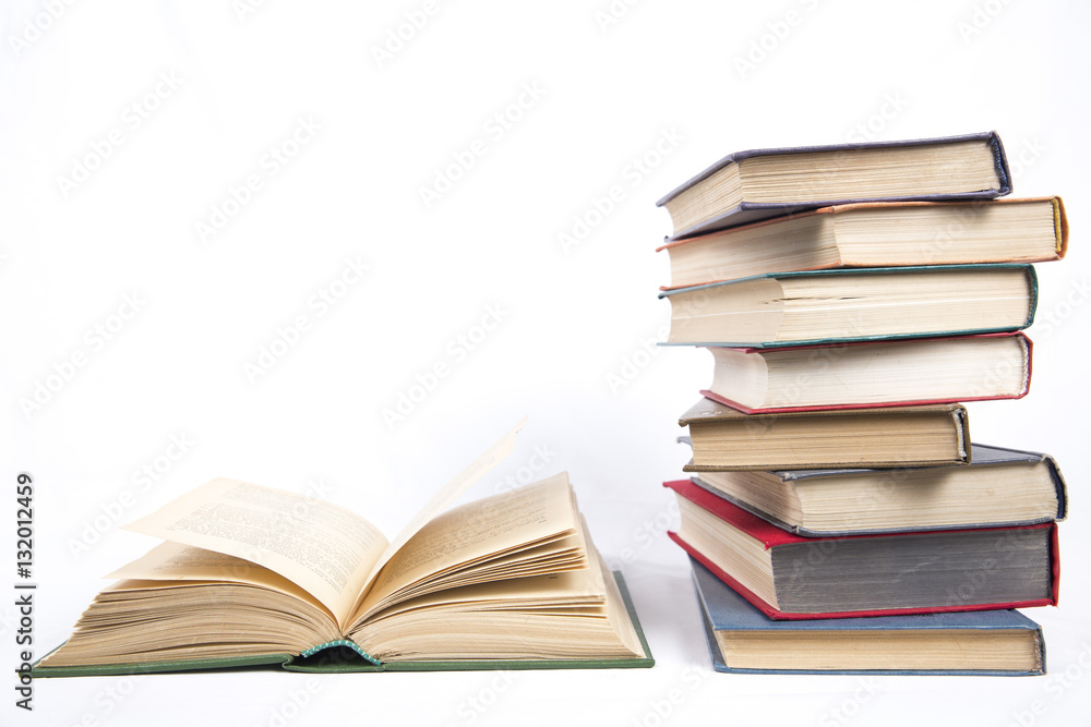 open book in hardcover on a table next to an uneven stack of boo open book in hardcover on a table next to an uneven stack of boo