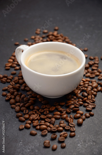 Cup of fresh coffee with coffee beans on black background, vertical, selective focus. © julijadmi