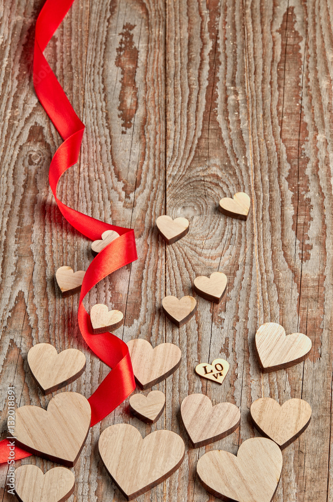 Different size heart figures on wooden background with red ribbon