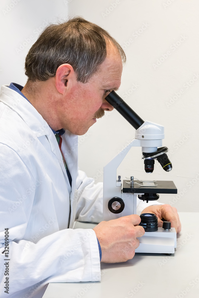 Biologist in lab coat looking through microscope Biologist in lab coat looking through microscope