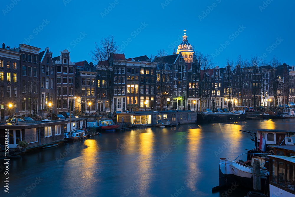 Fototapeta premium Canal in Amsterdam with houseboats in the blue evening light, t