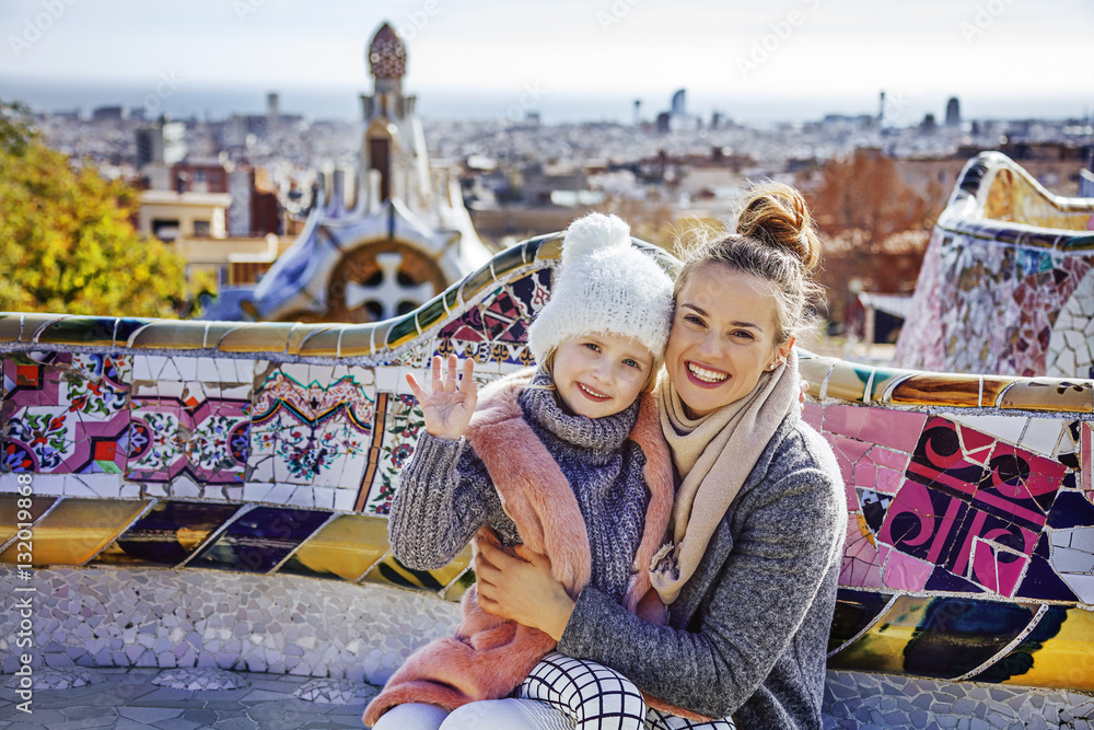 Naklejka premium matka i dziecko w Barcelonie handwaving siedząc na ławce