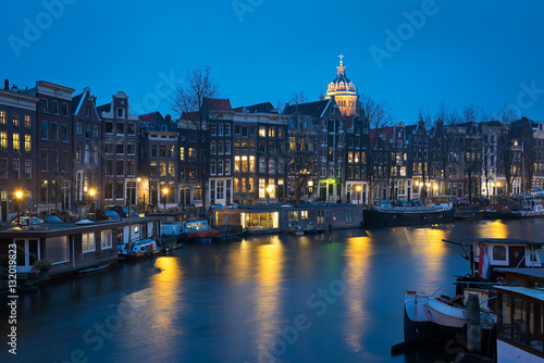 Canal in Amsterdam with houseboats  in the blue evening light, t