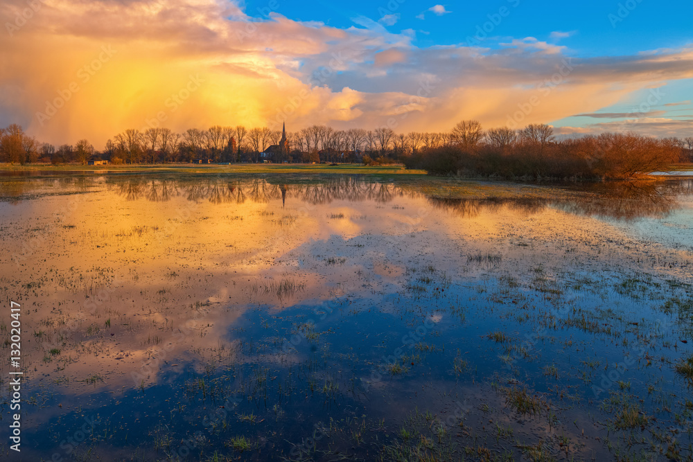 Goldene Wolken / Wolkenspiegelung auf einer Wiese bei Dannenberg (Landkreis Lüchow-Dannenberg, Niedersachsen). Aufgenommen während der goldenen Stunde vor dem Sonnenuntergang vom 24. Februar 2016.