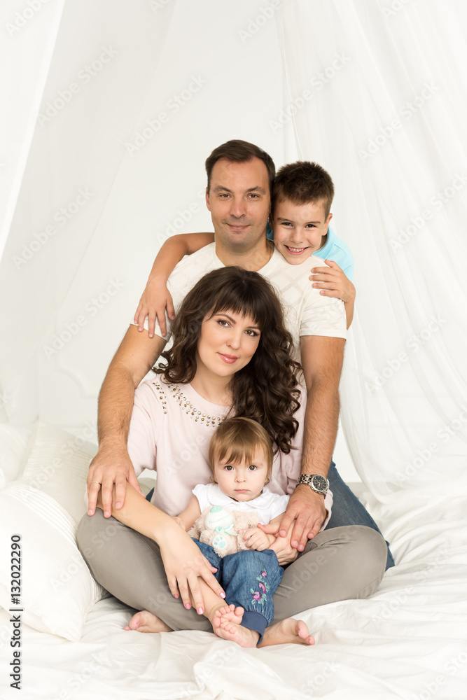 Family. Father, mother, son, daughter sitting on the bed