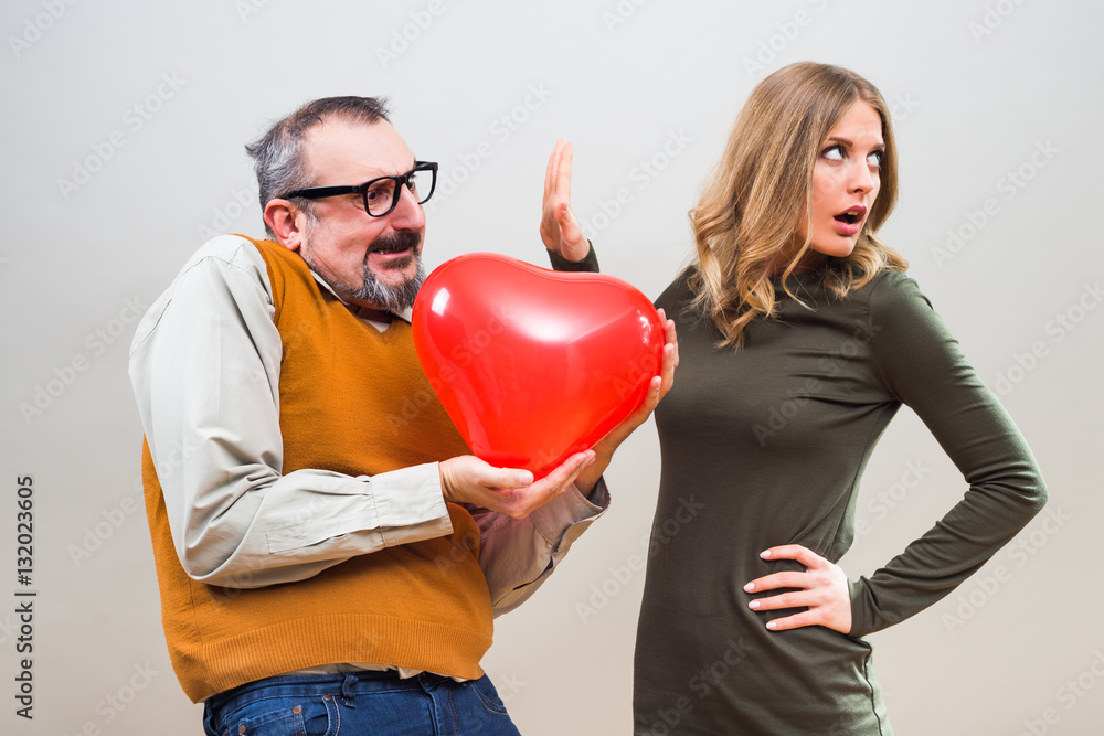 Nerdy man wants to give heart shape balloon to a beautiful woman to show her his love,but she is not interested.
Nerdy man wants to give heart shape balloon to a beautiful woman to show her his love,but she is not interested.