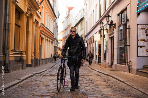 Hipster man in the city walking down the street with bicycle