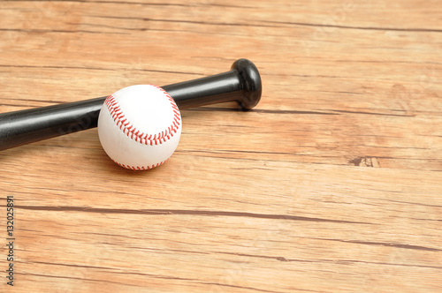 A baseball bat and ball isolated on a wooden background