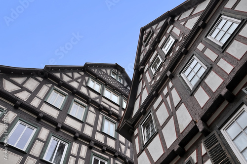 Look up at two old typical half-timbered houses of black frame and white stucco. Waiblingen, Baden-Wurttemberg, Germany.