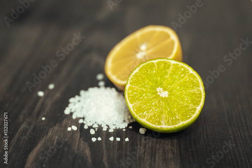 Fresh sliced lime, lemon and salt on wood table