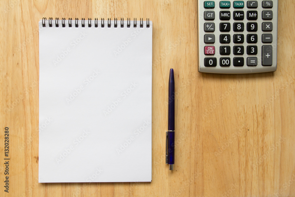 Blank paper note book with pen, calculator on wood table Blank paper note book with pen, calculator on wood table