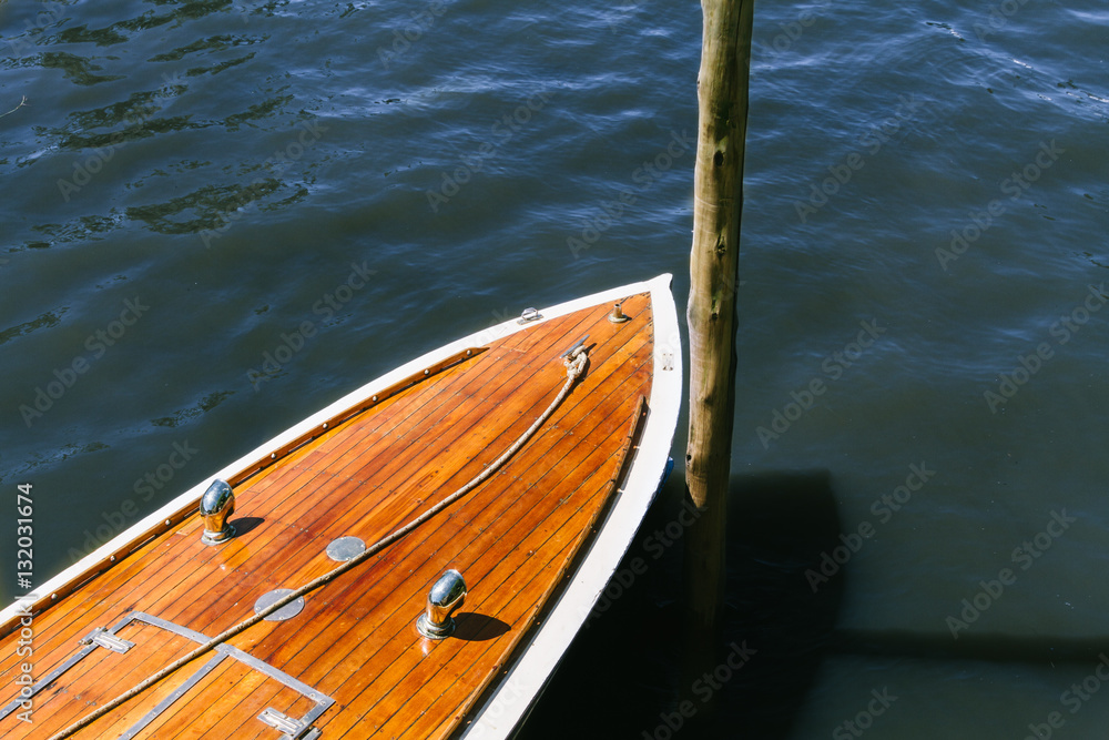 Obraz premium Detail of the wooden deck of a boat moored to a wooden stick