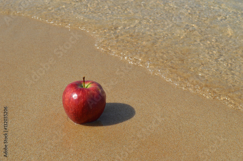 Red apple on the sandy beach