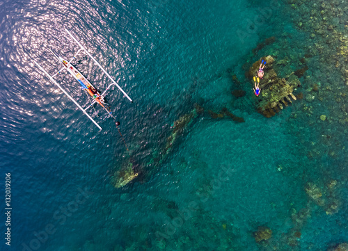 Aerial shot of the Japanese ship wreck with boat and people snorkeling over it. Bali, Indonesia