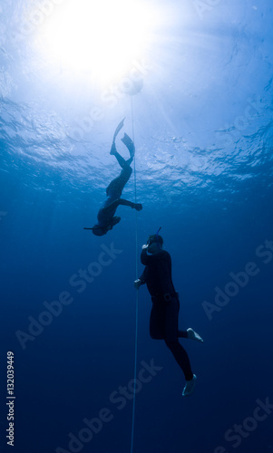 Free diver ascending along the rope in the depth