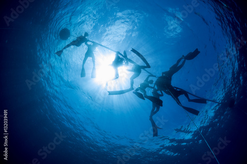 Free divers on the ocean's surface preparing to descend to the depth