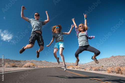 Three young friends jumping and having fun on the empty asphalt road