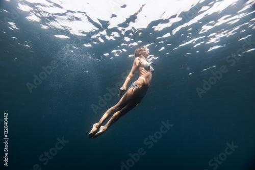 Underwater shot of the young lady moving towards the surface