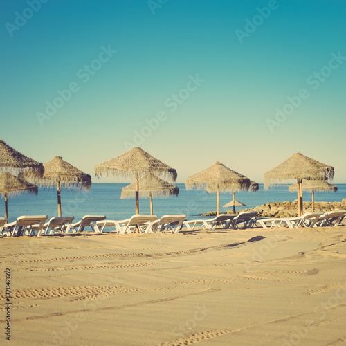 Holiday and vocation image with sandy beach  parasol and chairs on outdoors background