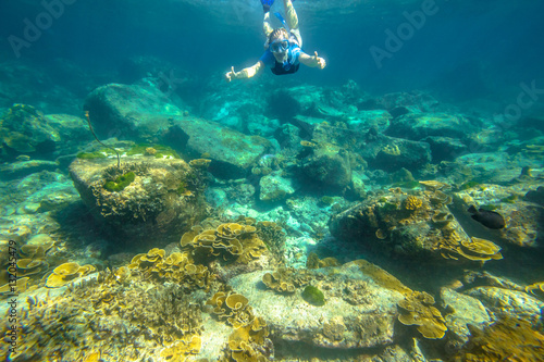 Female apnea swims in tropical turquoise sea of Racha Noi, Phuket in Thailand.