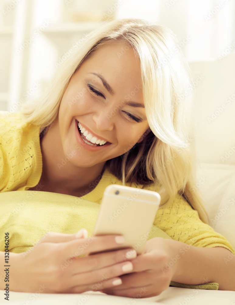 Happy blonde girl with a smartphone at home Happy blonde girl with a smartphone at home