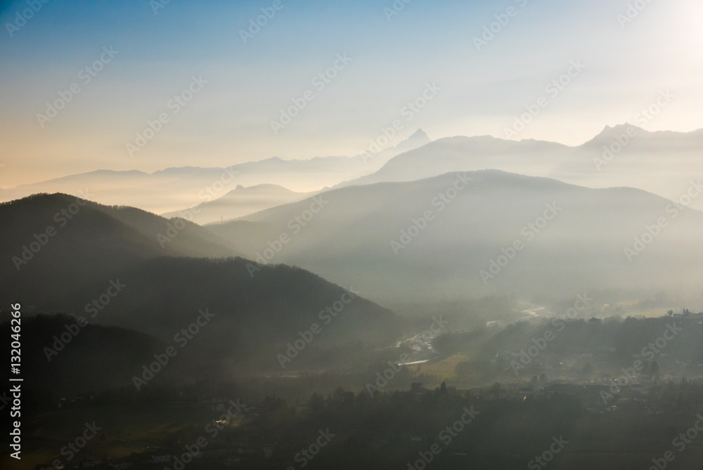 Blue toned mountain silhouette and foggy valleys in winter