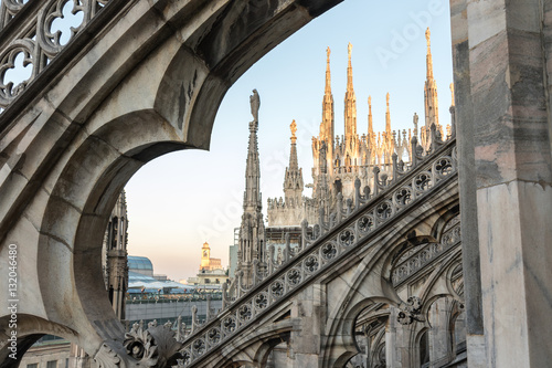 Details of marble spiers and statues of Milan Cathedral, Italy, at sunset.