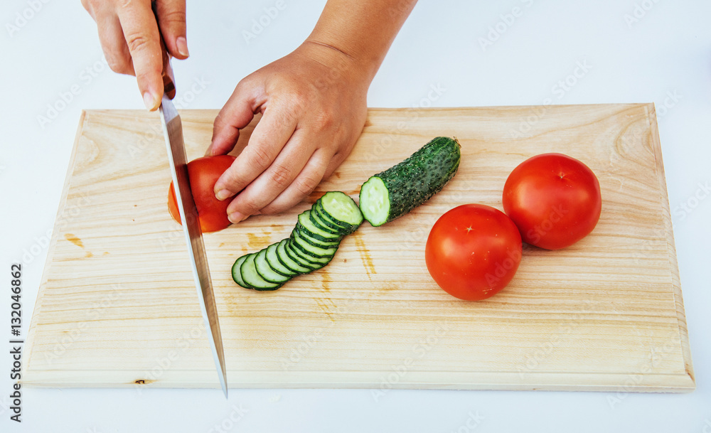 Wooden board with a knife and tomato and cucumber Wooden board with a knife and tomato and cucumber