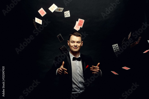 Closeup of man magician with two playing cards in his hand over grey background