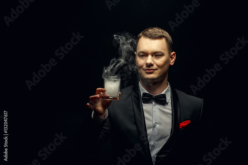 Illusionist man makes smoke his hand on a dark background.